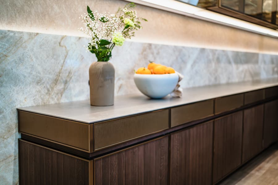 Warmte in de keuken.jpg Donker houte keuken met een beige marmer achterwand