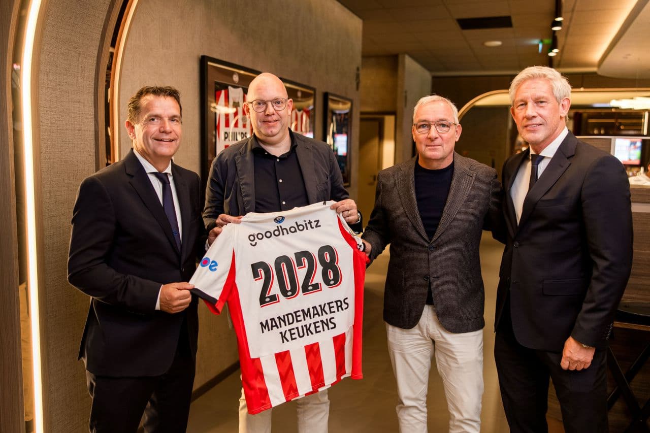 1758716344046.jpg Foto van vier mannen op een rij waarbij een man een PSV shirt vasthoudt