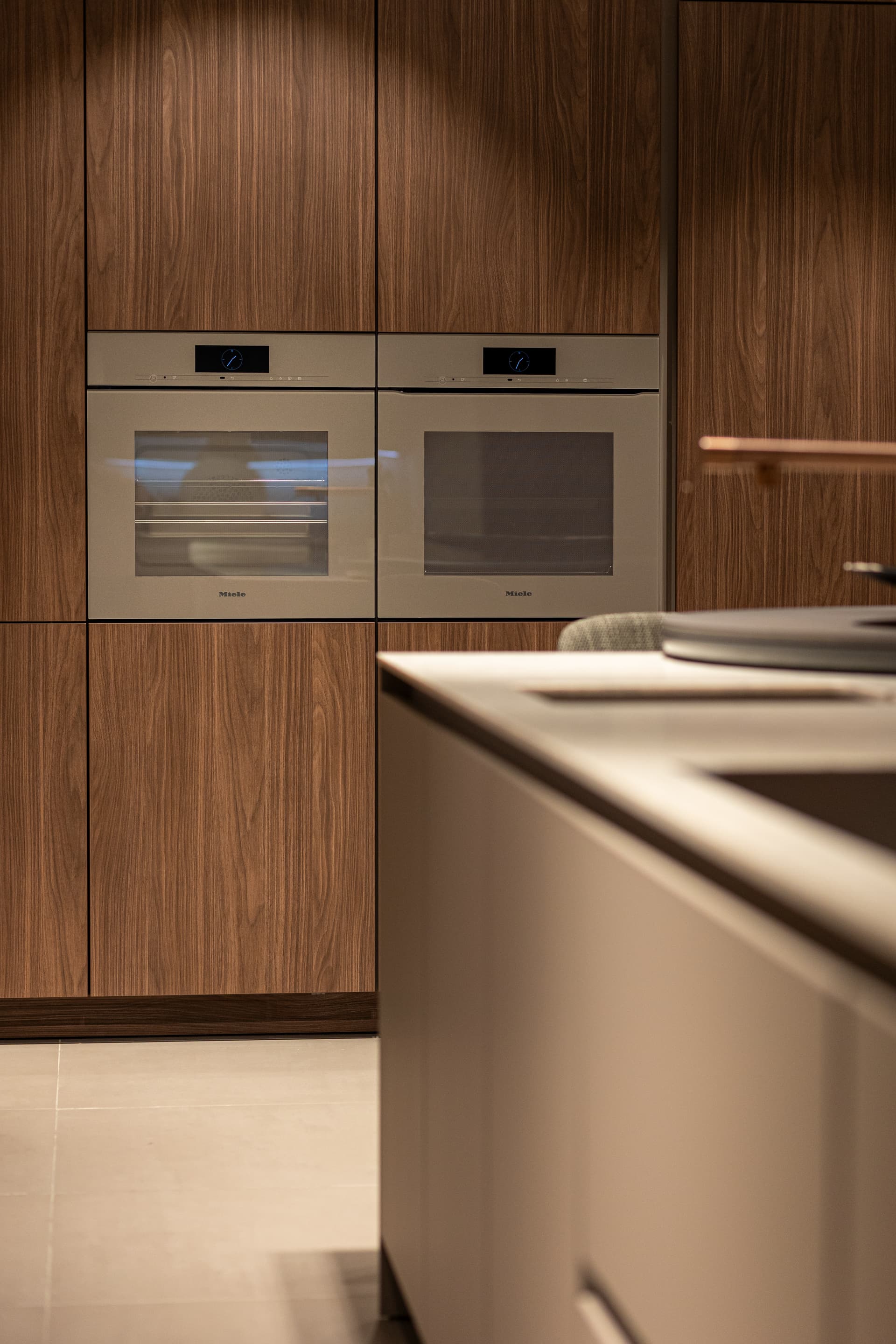 Meer lef(2).png Donker houten hoge keukenkasten met twee beige ovens naast elkaar